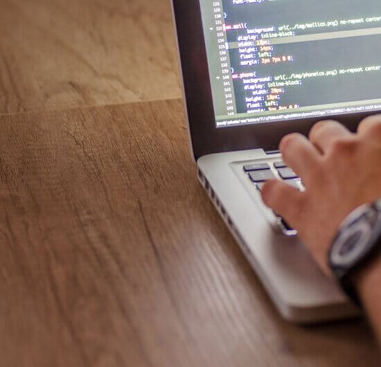 Close-up of a person coding on a laptop, showcasing web development and programming concepts.