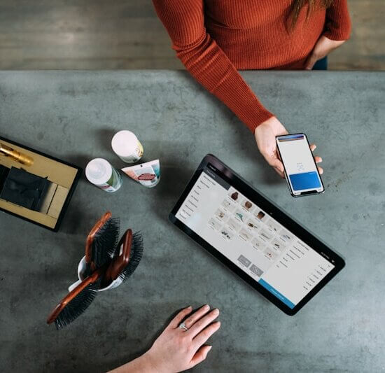 person holding smartphone beside tablet computer